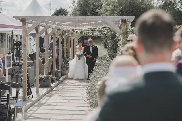 A bride and her father under the wisteria pergola
