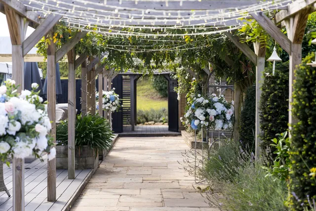 The pergola aisle lit with fairy lights