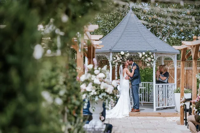 A first kiss framed by gazebo florals