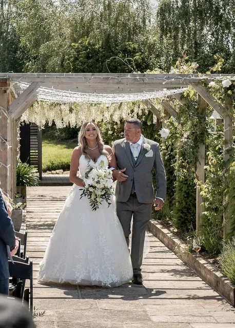 A bride and her father under the floral arch