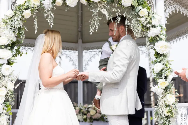A couple exchanging rings at the gazebo in summer