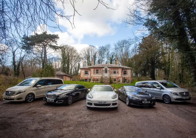 A fleet of executive cars lined up outside a country house