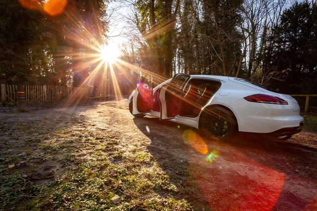 A luxury car on a woodland lane at sunrise