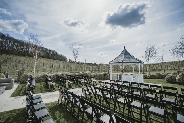 Rows of chairs facing the Orchard Garden gazebo with the orchards behind