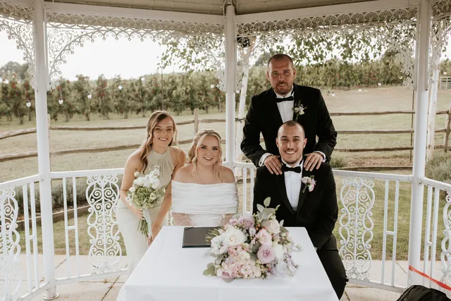 A couple sign the register with their witnesses at the Orchard Garden gazebo