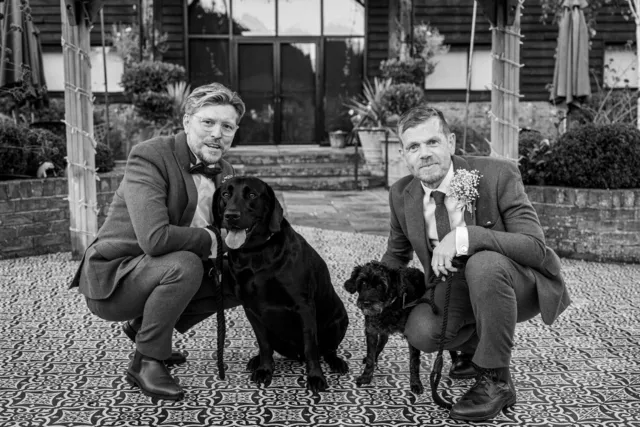 Two grooms with their dogs, in black and white
