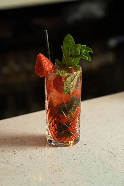 A tall strawberry and mint cocktail in a cut glass