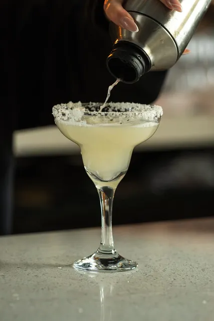 A margarita being poured into a salt rimmed glass
