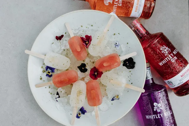 Watermelon ice lollies served on a bed of ice with edible flowers