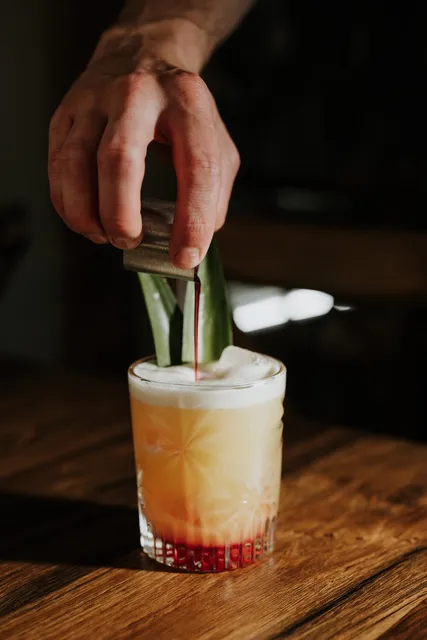 A long drink being built over ice with cucumber