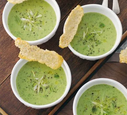 Chilled pea soup served in small bowls with cheese crisps