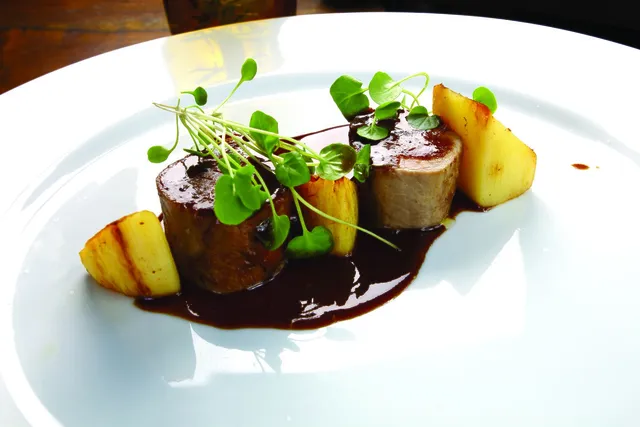 A plated main with a rich jus and micro herbs