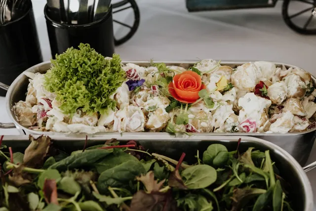 A long platter of salad with a tomato rose