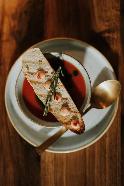 Soup with a rosemary crostini and a gold spoon