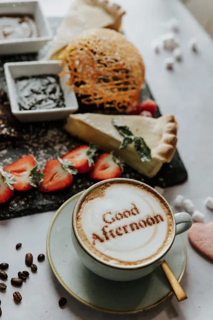 A cheese board with strawberries and a cappuccino