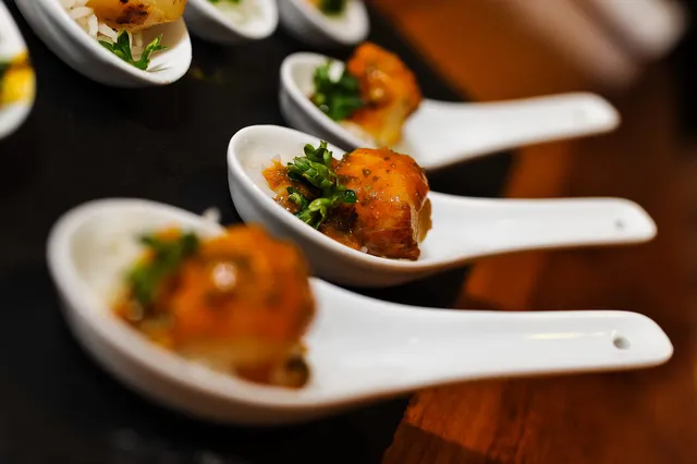 A close up of canape spoons with a herb garnish