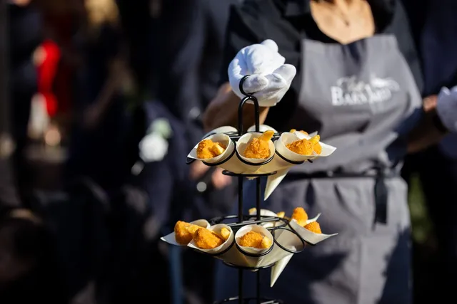 A waiter carrying a tiered stand of canapes