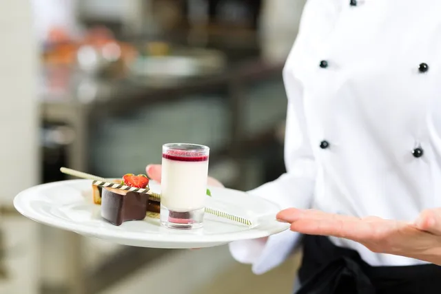 A waiter carrying a plated dessert