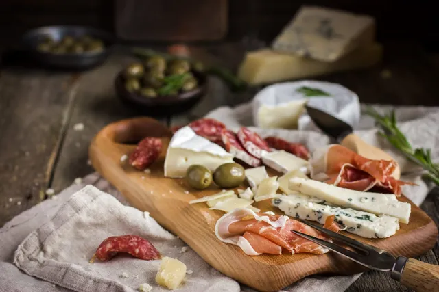 A charcuterie board with olives and cheese