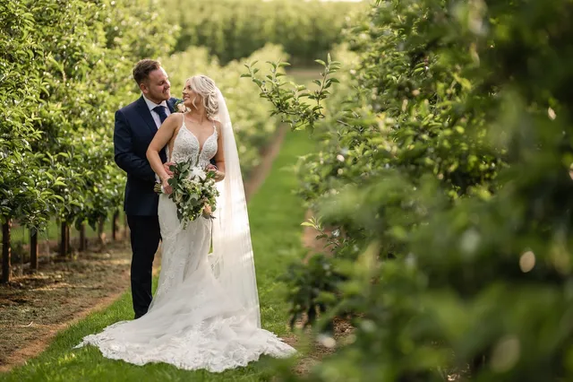A couple among the apple trees with a summer bouquet