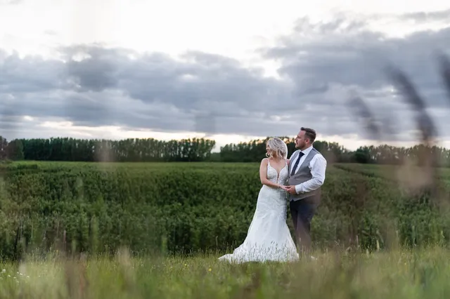 A couple in the fields under a dramatic sky