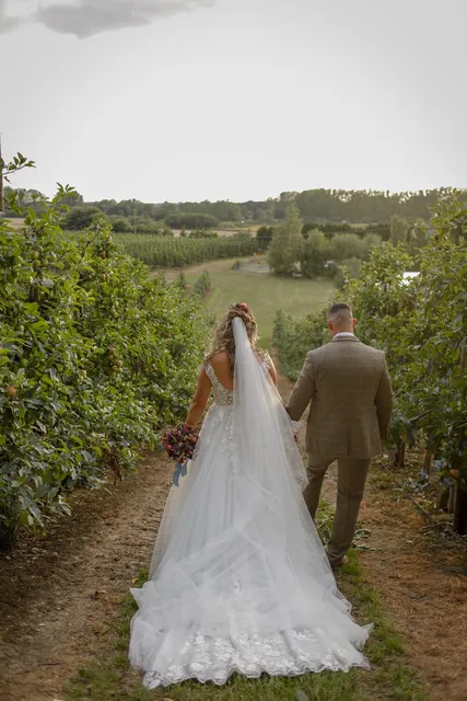 A couple walking hand in hand through the orchard