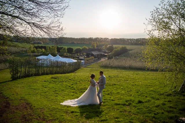 A couple in the field with the marquee behind