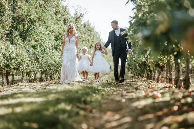 A couple walking the orchard with their flower girls