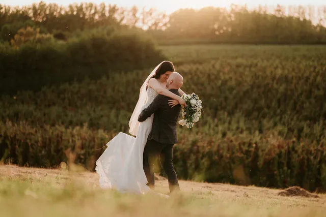 A groom lifting his bride in the golden fields