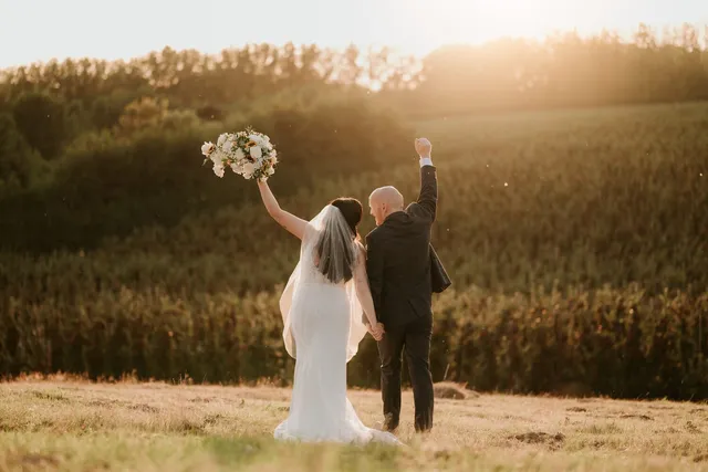 A couple cheering with the bouquet at sunset