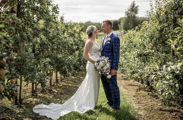 A couple with a trailing bouquet among the trees