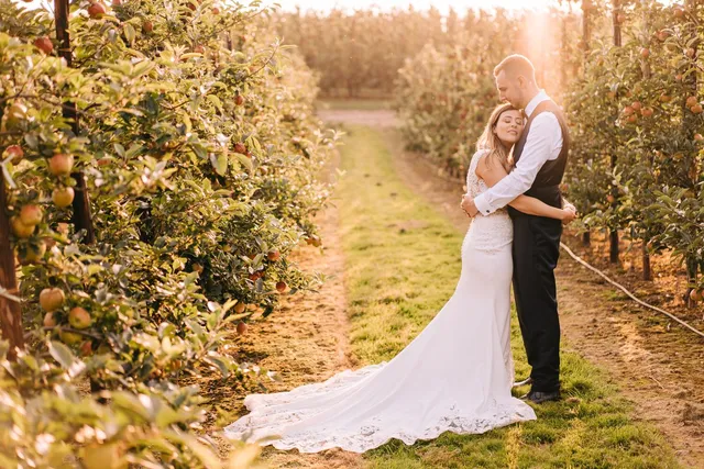 A bride's train spread down the orchard row