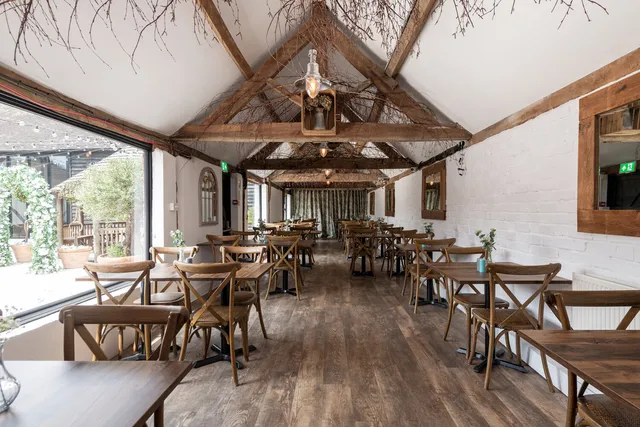 Tables set beneath the exposed trusses at The Roost