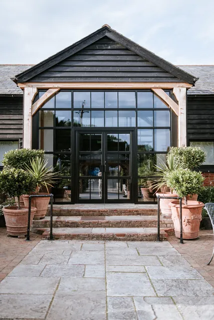 The entrance to The Rooster framed by potted olive trees