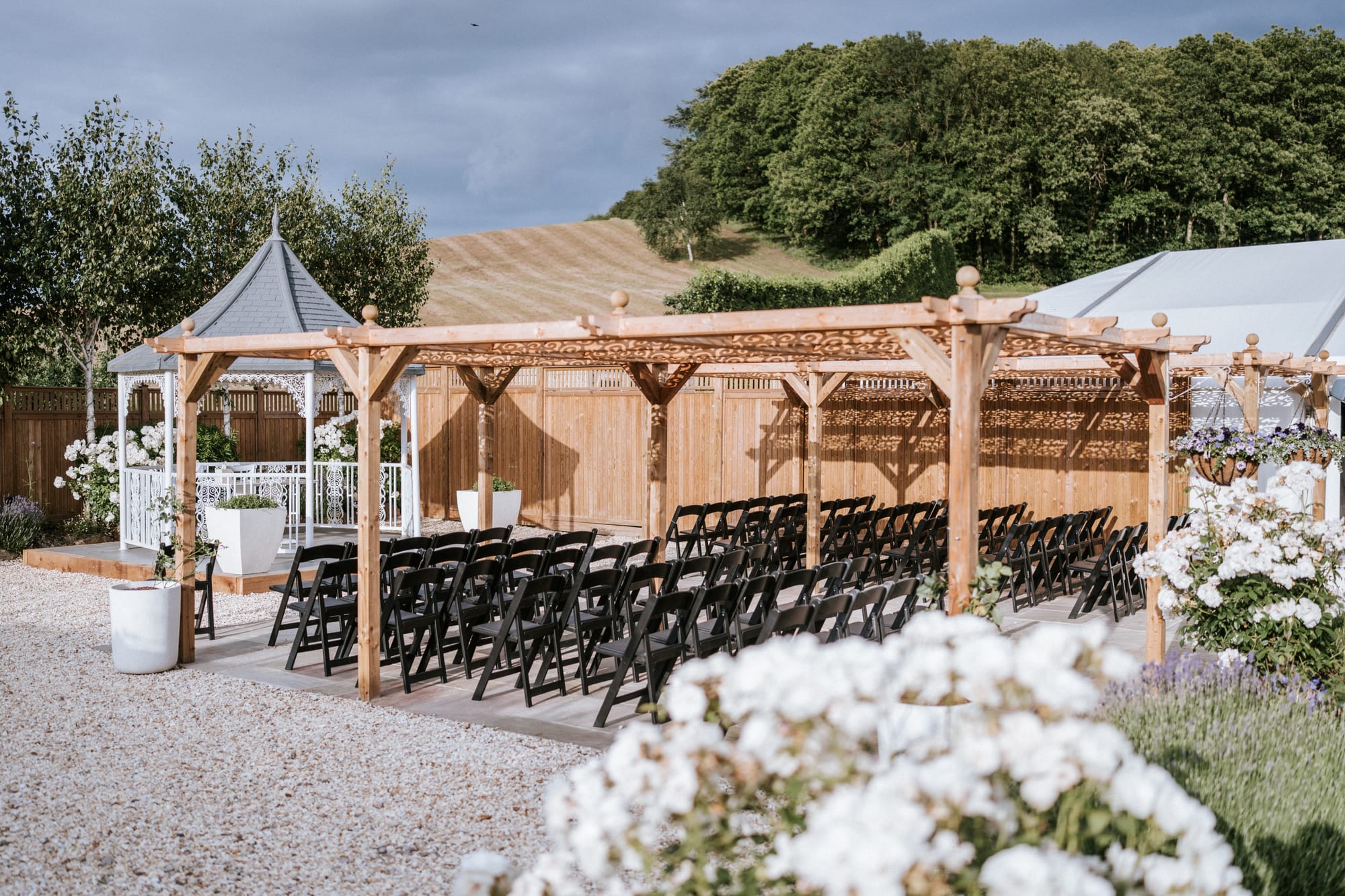 The ceremony pergola at The BarnYard set with chairs, with white blossom in the foreground