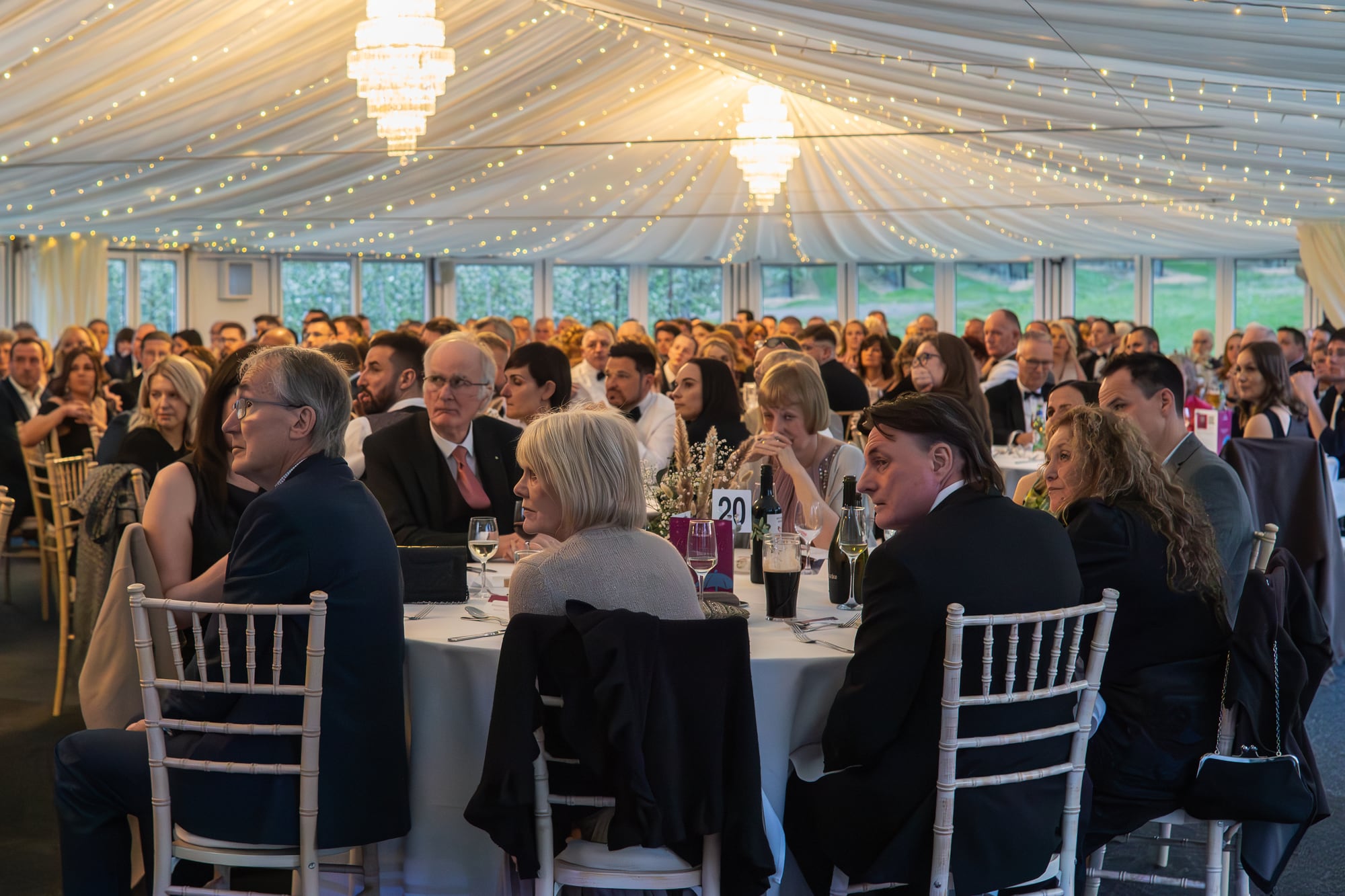A company dinner at The BarnYard, with round tables filling the Arboretum pavilion
