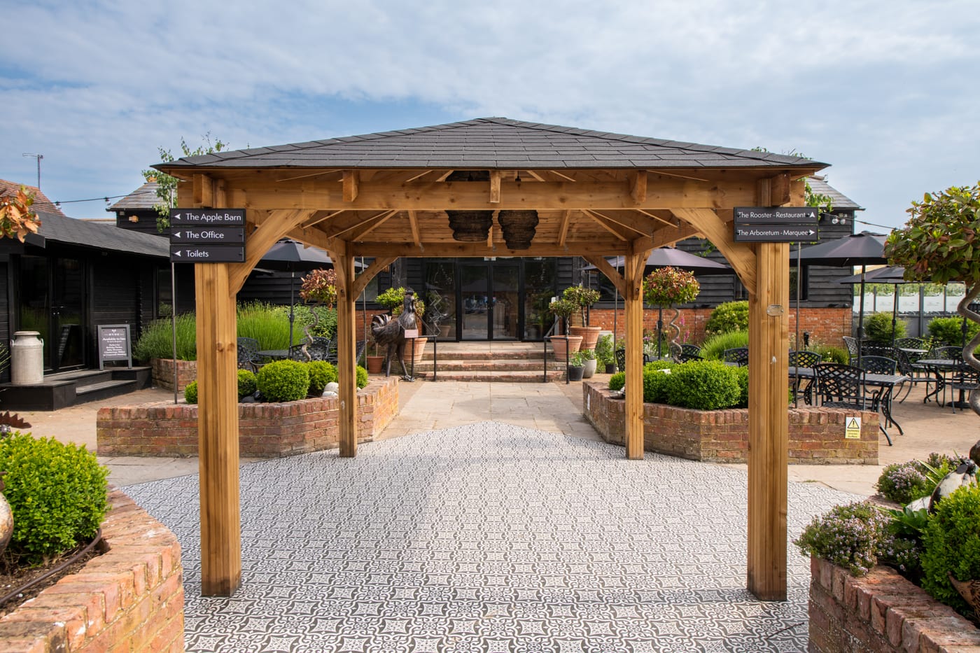 The covered Courtyard terrace at The BarnYard, with planted borders and outdoor seating