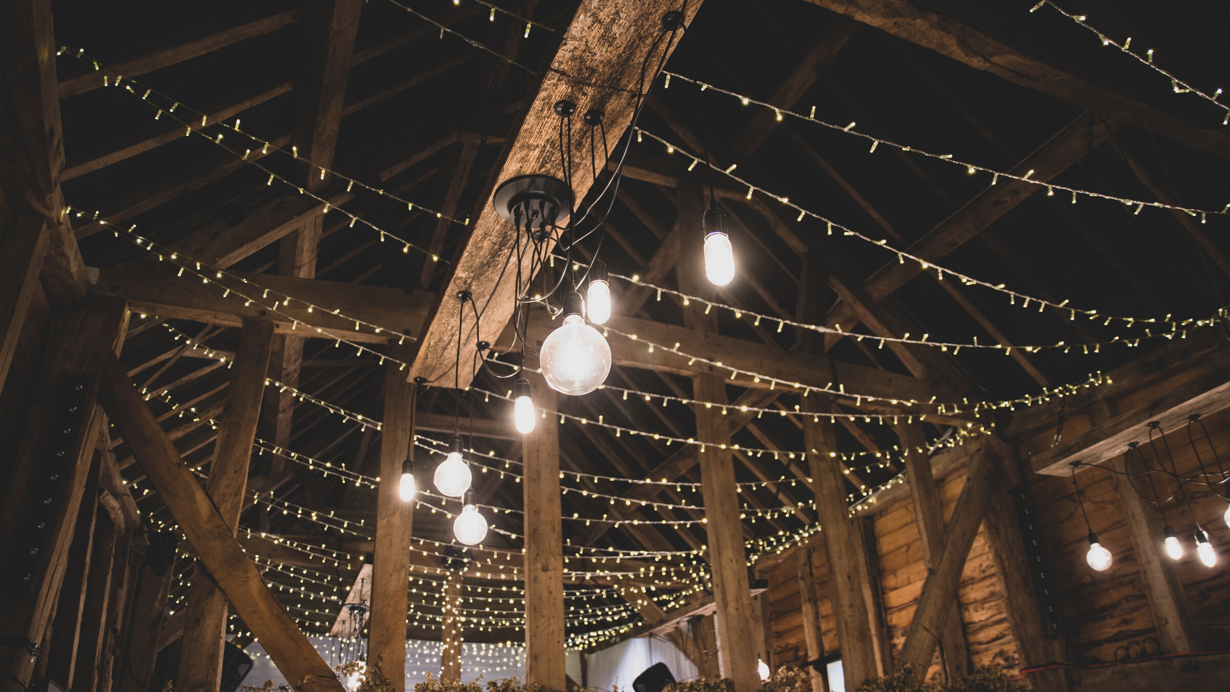 The oak rafters of the Apple Barn draped in thousands of fairy lights