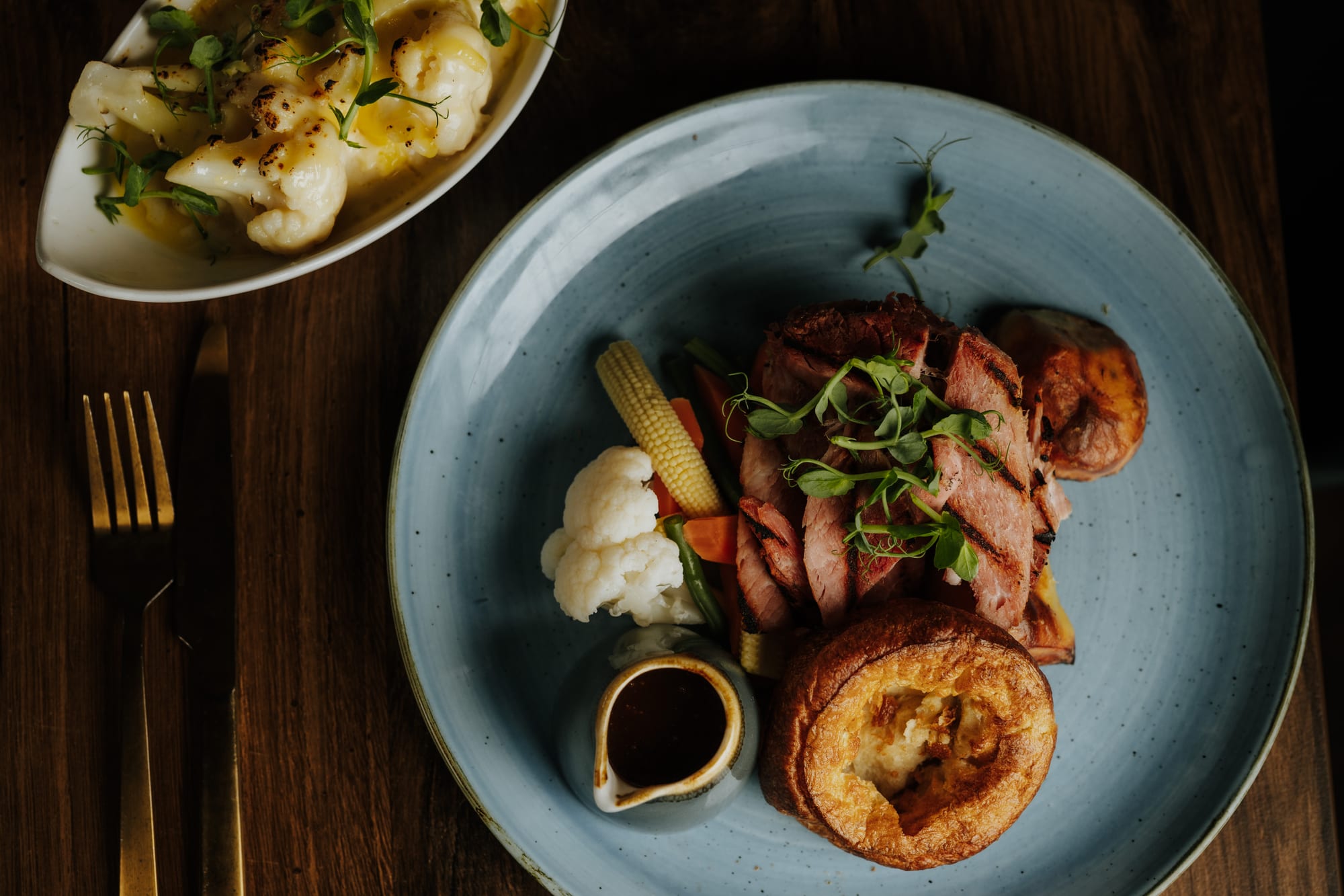 A plated Sunday roast at The BarnYard in Kent, with beef, Yorkshire pudding and a jug of gravy
