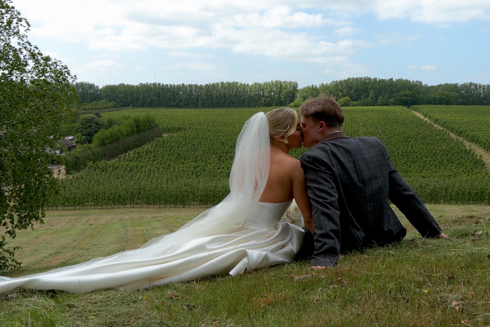 A couple seated on the hillside at The BarnYard, looking out across the orchards