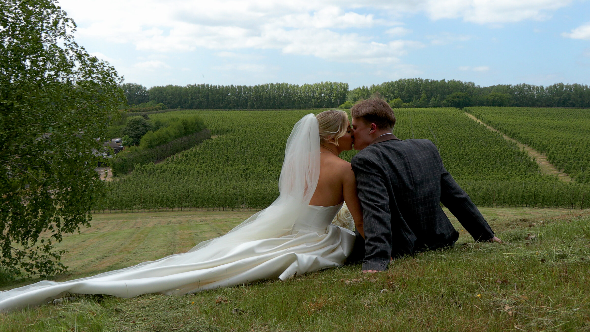 A couple seated on the hillside at The BarnYard, looking out across the orchards