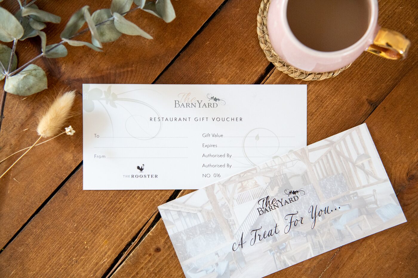 A BarnYard restaurant gift voucher and its Treat For You envelope on a wooden table