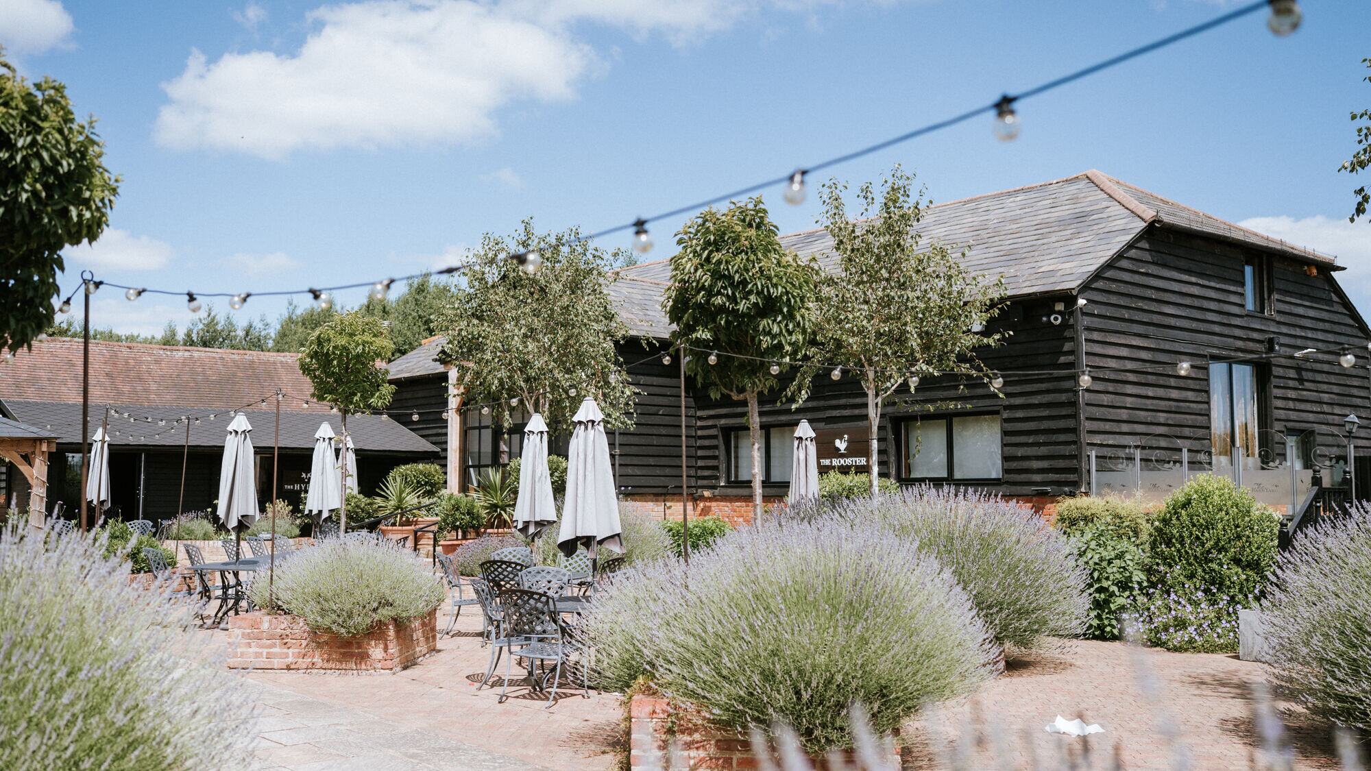 The lavender terrace outside The Rooster at The BarnYard, tables set under the festoon lights