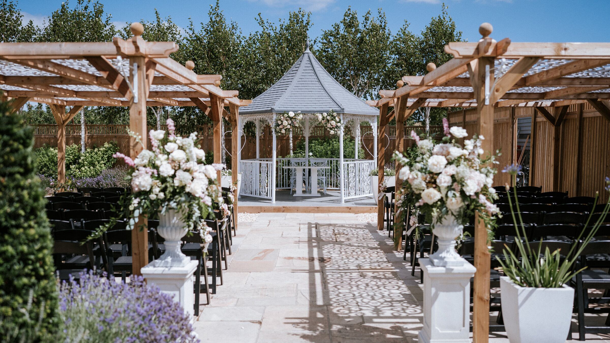 The Lavender Walk gazebo dressed with florals for a ceremony, chairs set beneath the pergolas at The BarnYard in Kent