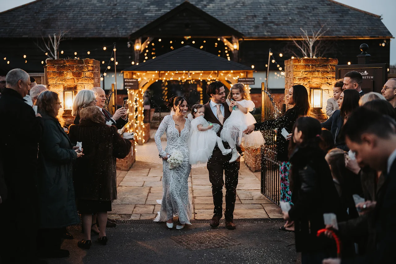 A couple walking through a confetti send-off at dusk at The BarnYard