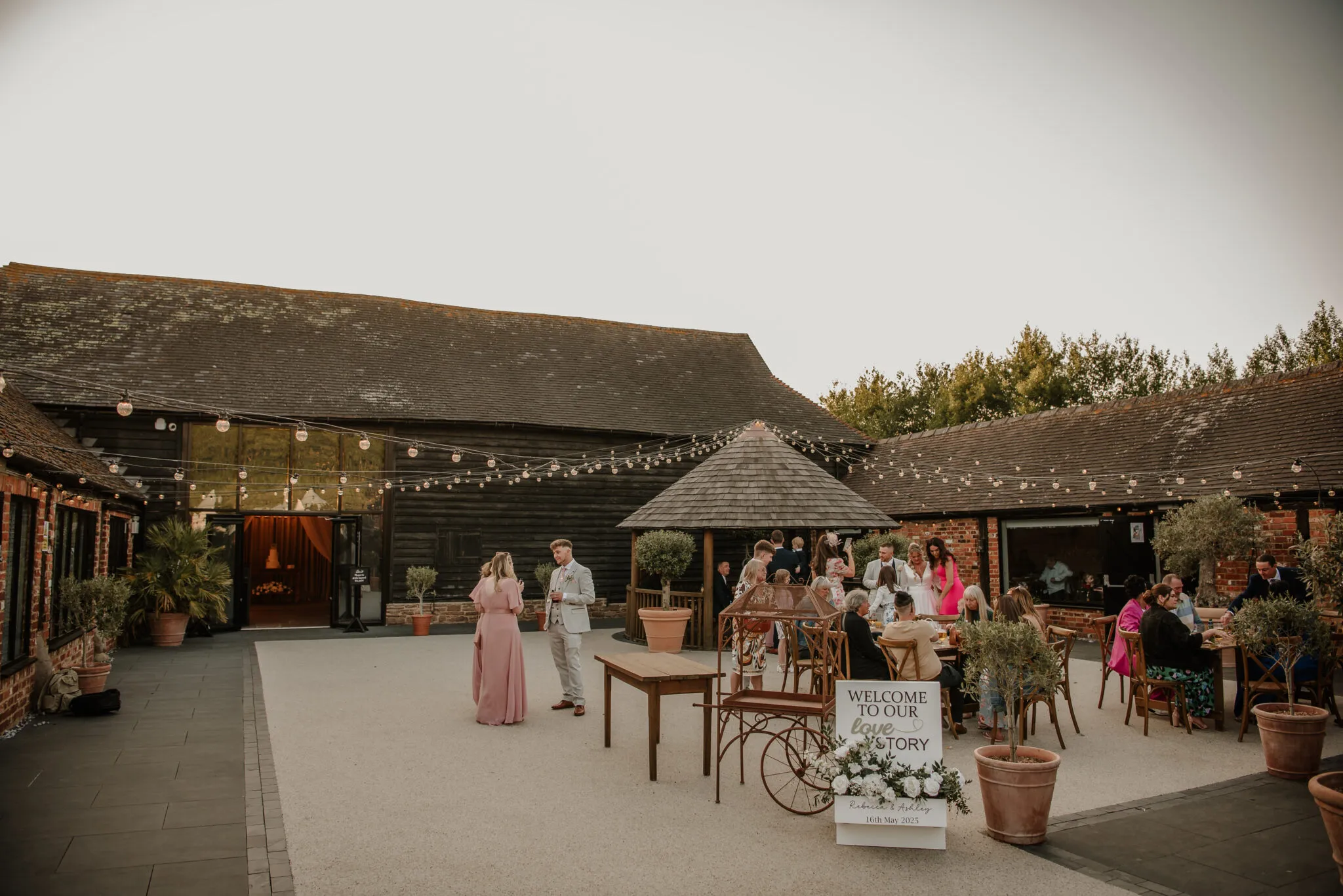 Guests enjoying evening drinks beneath the festoon lights in the Courtyard at The BarnYard
